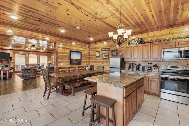 kitchen with stainless steel appliances, light stone countertops, an inviting chandelier, wooden ceiling, and a center island