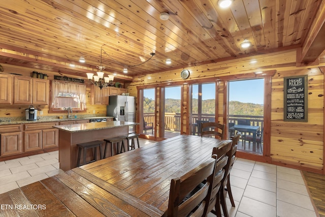 tiled dining area featuring wood walls and a healthy amount of sunlight