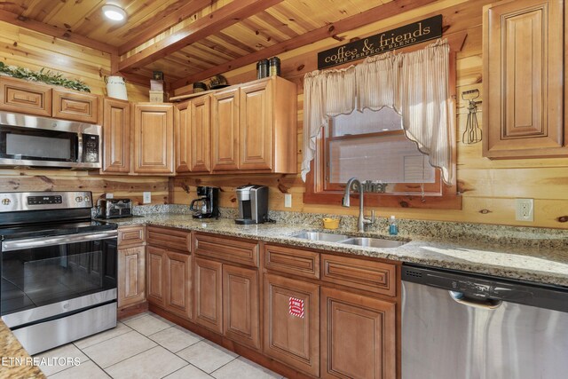 kitchen featuring light tile patterned flooring, beamed ceiling, sink, light stone counters, and appliances with stainless steel finishes