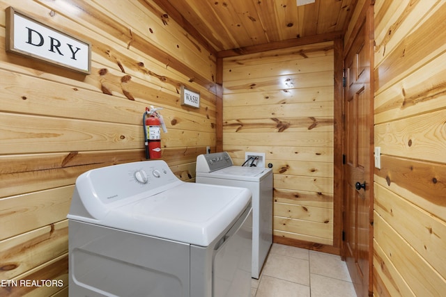 washroom featuring wood walls, washing machine and dryer, light tile patterned flooring, and wooden ceiling