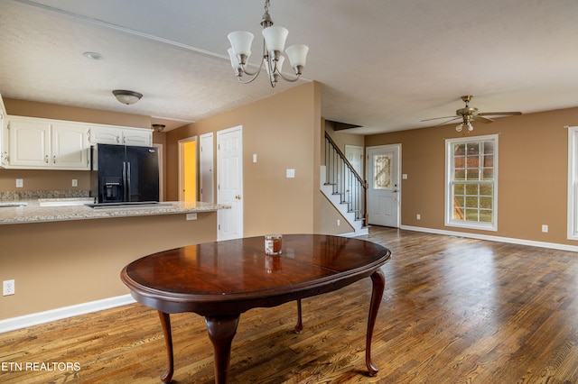 dining area with ceiling fan with notable chandelier and hardwood / wood-style flooring