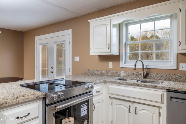 kitchen with light stone countertops, white cabinetry, sink, and appliances with stainless steel finishes