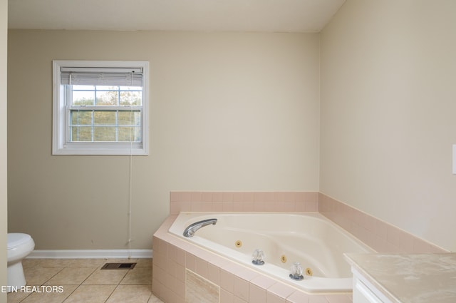 bathroom featuring tiled tub, tile patterned flooring, and toilet