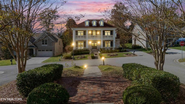 view of front of home with a garage, curved driveway, and a balcony