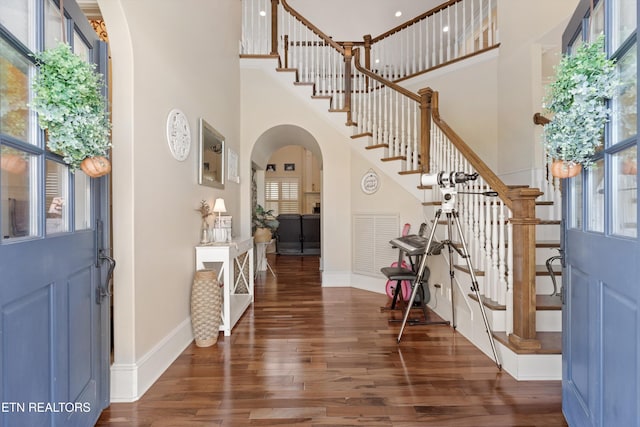 entryway with a towering ceiling and dark hardwood / wood-style flooring