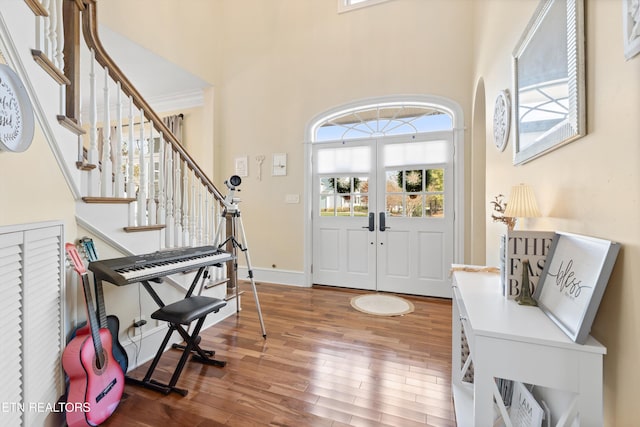 foyer with a high ceiling, wood-type flooring, and french doors