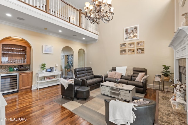 living room with a high ceiling, dark hardwood / wood-style floors, beverage cooler, and a tiled fireplace