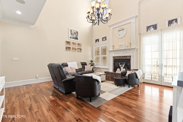 living room with hardwood / wood-style floors, a towering ceiling, an inviting chandelier, and plenty of natural light