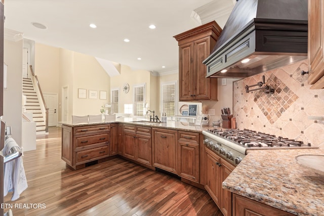 kitchen featuring light stone countertops, kitchen peninsula, premium range hood, sink, and dark hardwood / wood-style floors