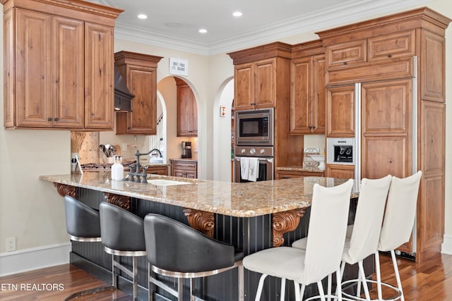 kitchen with dark hardwood / wood-style flooring, sink, appliances with stainless steel finishes, and a breakfast bar area