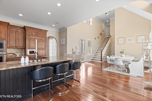 kitchen with light stone countertops, light wood-type flooring, a breakfast bar area, and sink