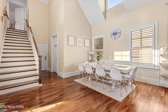 dining area featuring dark hardwood / wood-style flooring and a towering ceiling