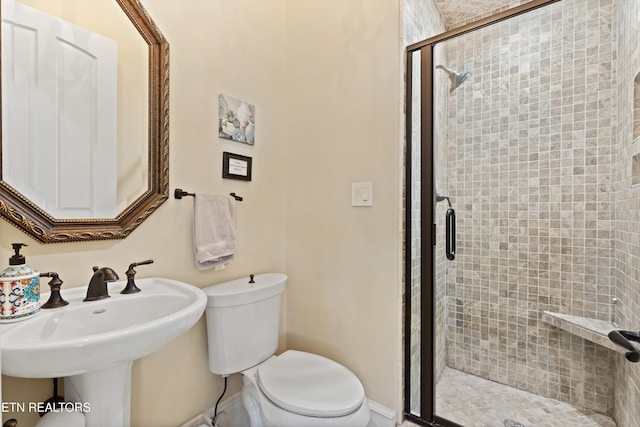 bathroom with toilet, a shower with shower door, and sink