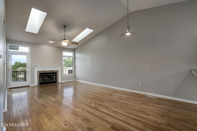 105 Poteau Trce, Loudon, TN 37774 - unfurnished living room with a skylight, hardwood / wood-style flooring, a tile fireplace, baseboards, and high vaulted ceiling