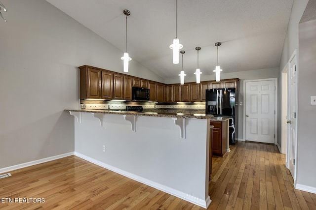 105 Poteau Trce, Loudon, TN 37774 - kitchen featuring black appliances, a kitchen bar, light wood-type flooring, tasteful backsplash, and vaulted ceiling