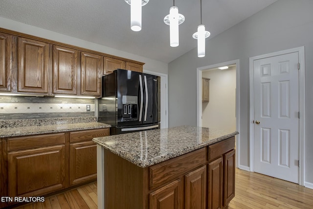 105 Poteau Trce, Loudon, TN 37774 - kitchen featuring black fridge, lofted ceiling, light wood-style flooring, light stone countertops, and decorative light fixtures