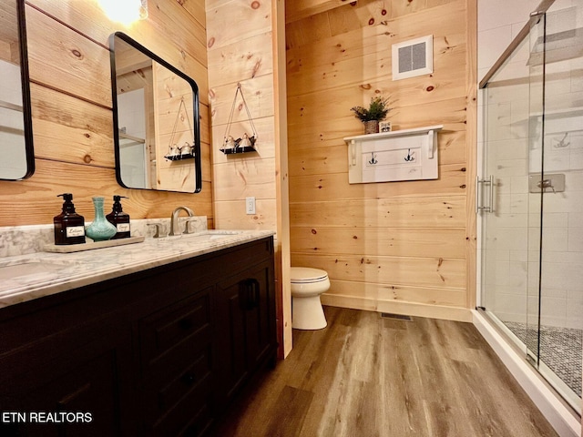 bathroom featuring walk in shower, wood walls, vanity, and hardwood / wood-style flooring