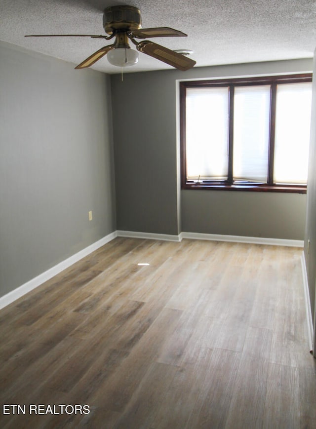 empty room with hardwood / wood-style floors, ceiling fan, and a textured ceiling