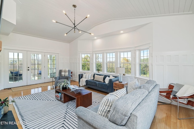 living room featuring vaulted ceiling, french doors, light wood-type flooring, and plenty of natural light