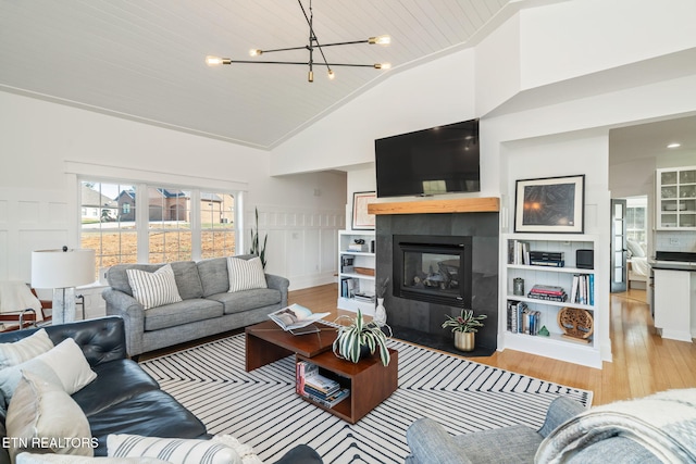 living room with high vaulted ceiling, a notable chandelier, wooden ceiling, light hardwood / wood-style floors, and a tiled fireplace