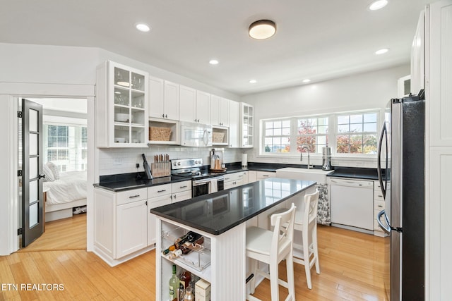 kitchen with white cabinets, a kitchen island, stainless steel appliances, and light hardwood / wood-style floors