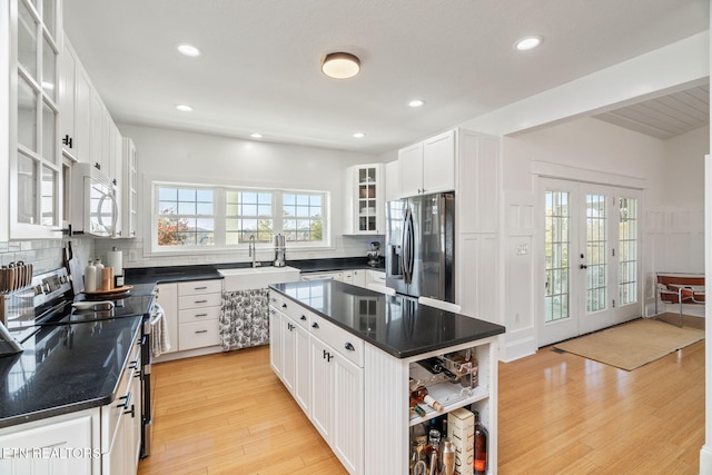 kitchen with white cabinetry, sink, a center island, light wood-type flooring, and stainless steel appliances