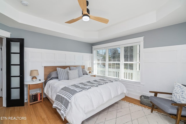 bedroom featuring a raised ceiling and light hardwood / wood-style floors