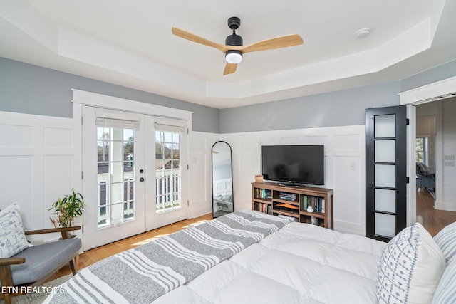 bedroom with access to exterior, ceiling fan, french doors, a raised ceiling, and light hardwood / wood-style flooring