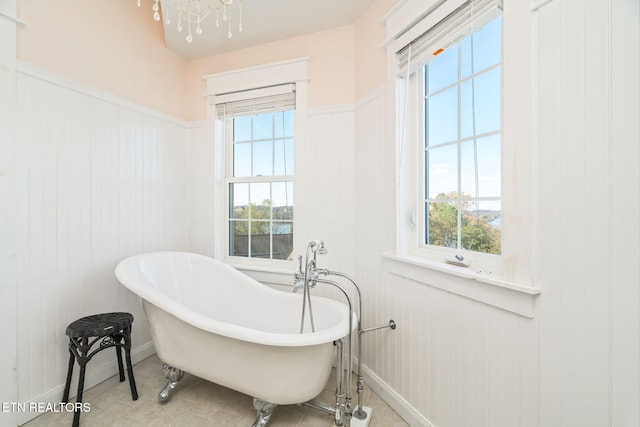 bathroom featuring a tub, a wealth of natural light, and an inviting chandelier