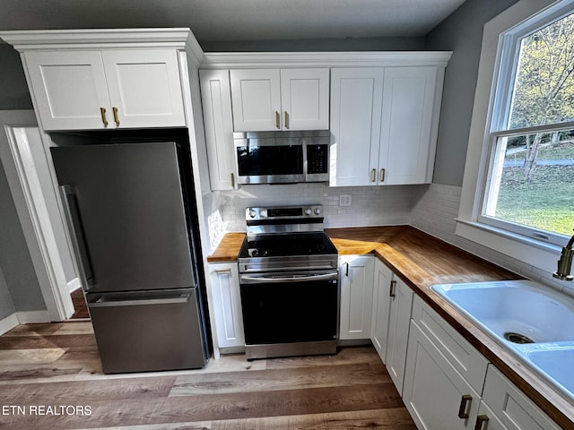 kitchen featuring white cabinets, a healthy amount of sunlight, stainless steel appliances, and butcher block counters