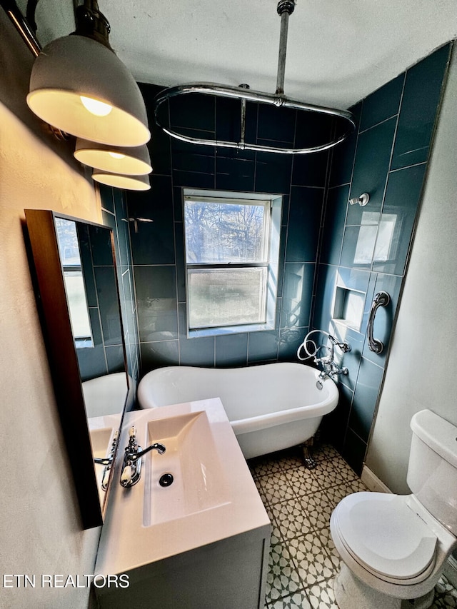 bathroom with toilet, a tub to relax in, sink, and a textured ceiling