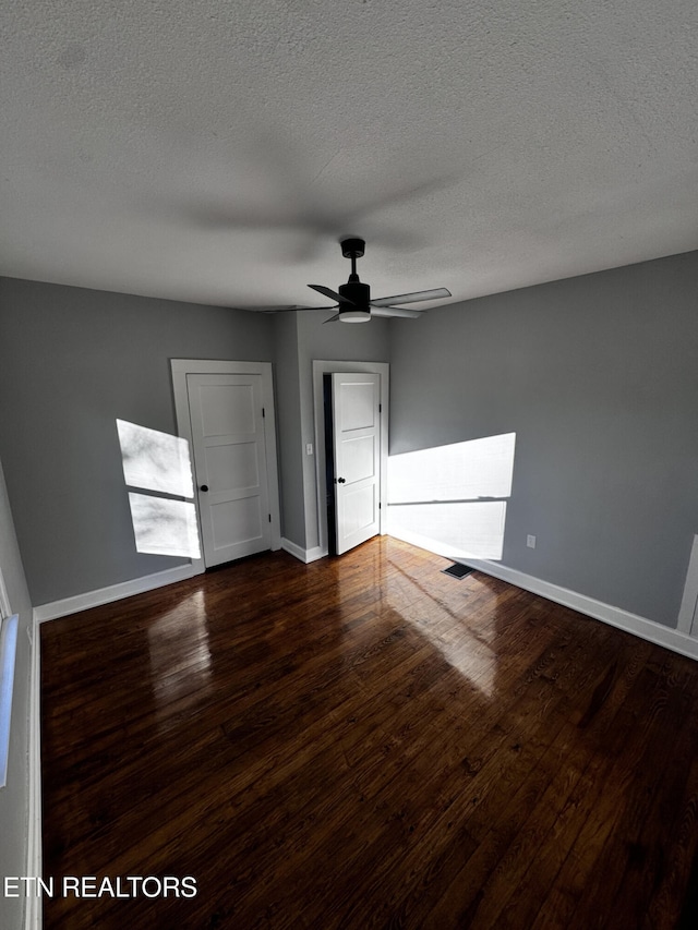 unfurnished room with a textured ceiling, dark hardwood / wood-style flooring, and ceiling fan