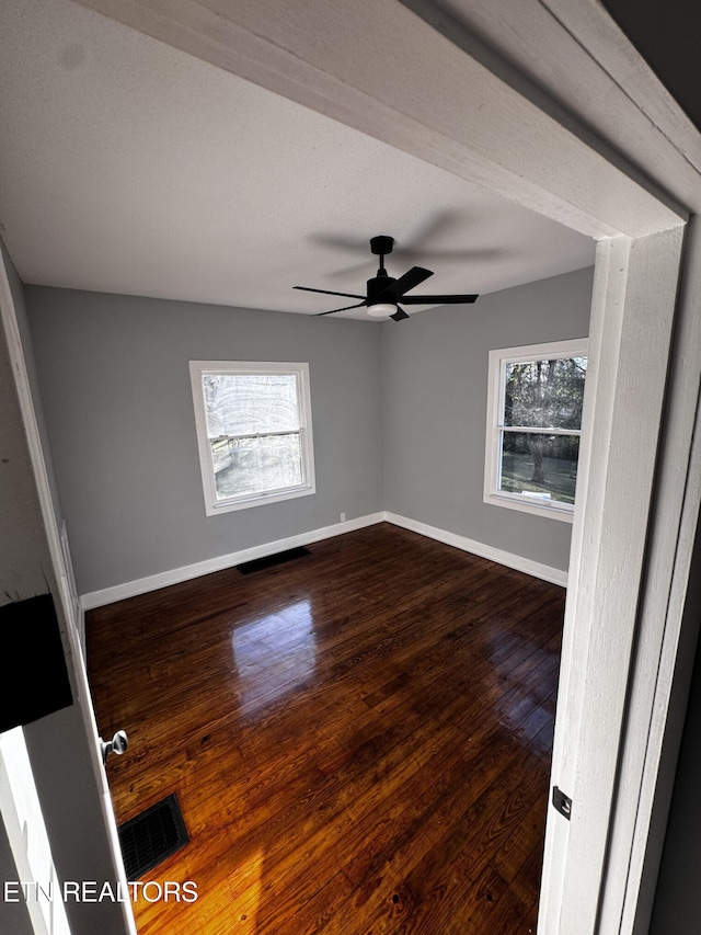 empty room with ceiling fan, plenty of natural light, and hardwood / wood-style floors