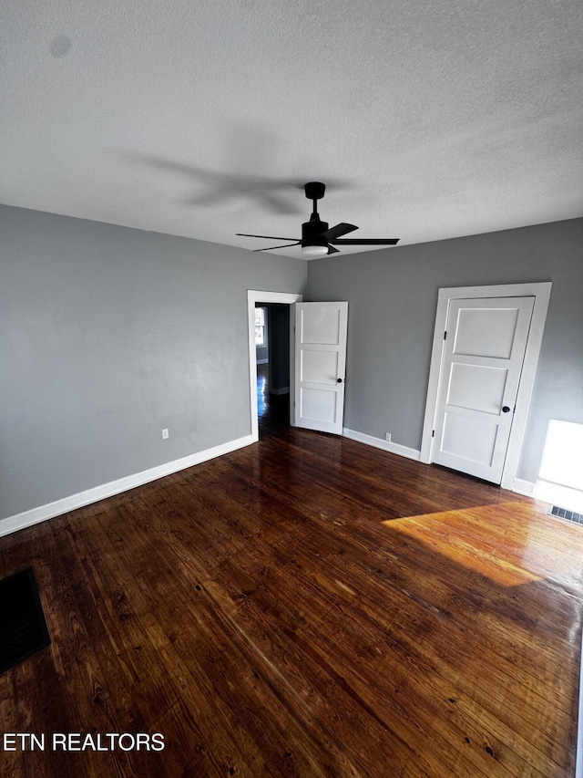 empty room with a textured ceiling, dark hardwood / wood-style floors, and ceiling fan