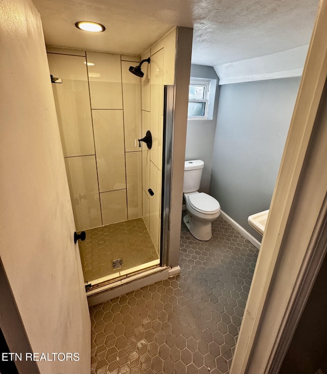 bathroom featuring tile patterned flooring, toilet, and a shower with door