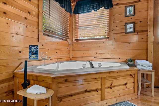 bathroom with hardwood / wood-style floors, a tub, and wooden walls