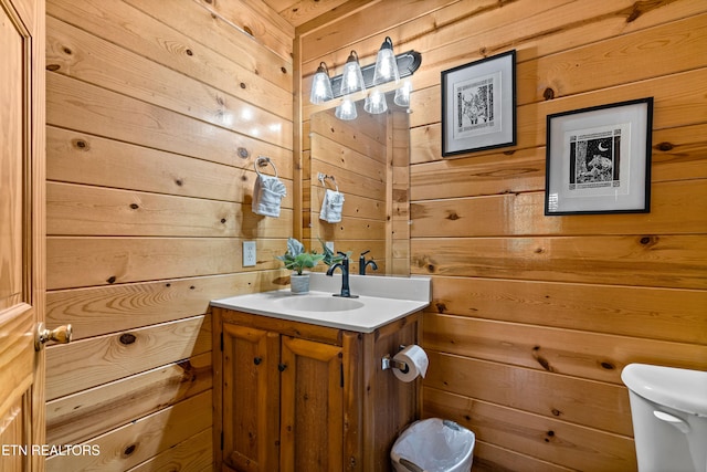 bathroom featuring vanity, wooden walls, and toilet