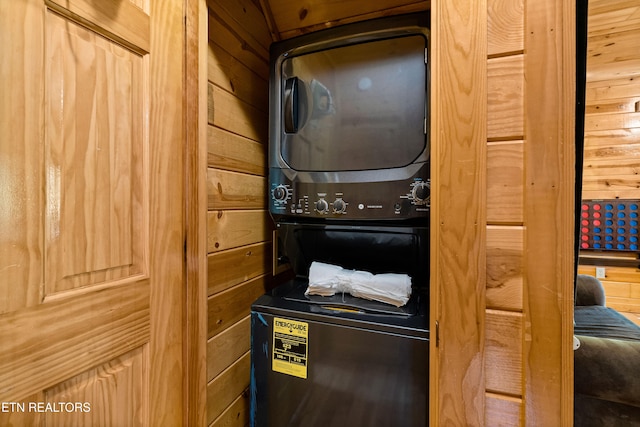 interior space featuring wood walls and stacked washer / dryer