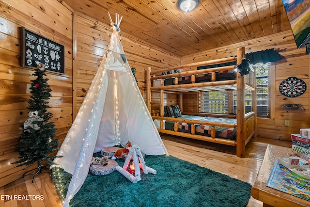 bedroom with hardwood / wood-style floors, wooden ceiling, and wood walls