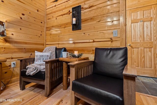 sitting room with light hardwood / wood-style floors and wood walls