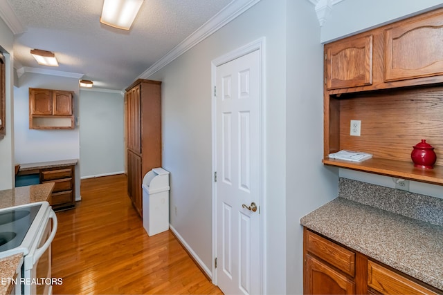 kitchen with light wood-type flooring, a textured ceiling, crown molding, and electric stove