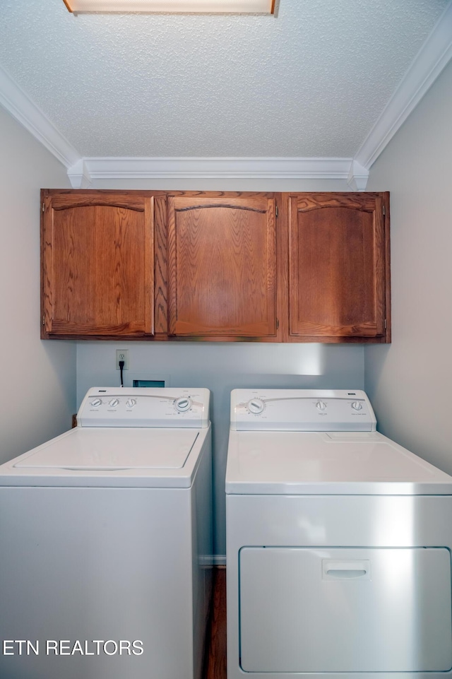 clothes washing area with cabinets, a textured ceiling, washing machine and dryer, and ornamental molding