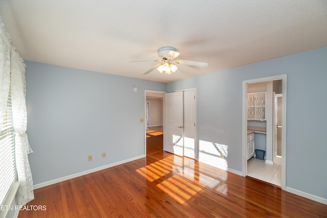 unfurnished bedroom with ensuite bathroom, light hardwood / wood-style flooring, and ceiling fan