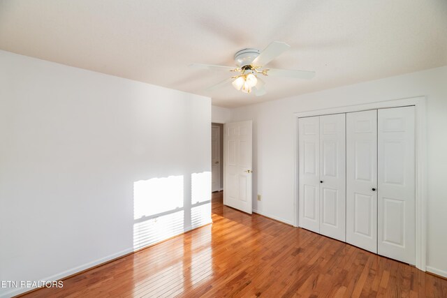 unfurnished bedroom with ceiling fan, wood-type flooring, and a closet