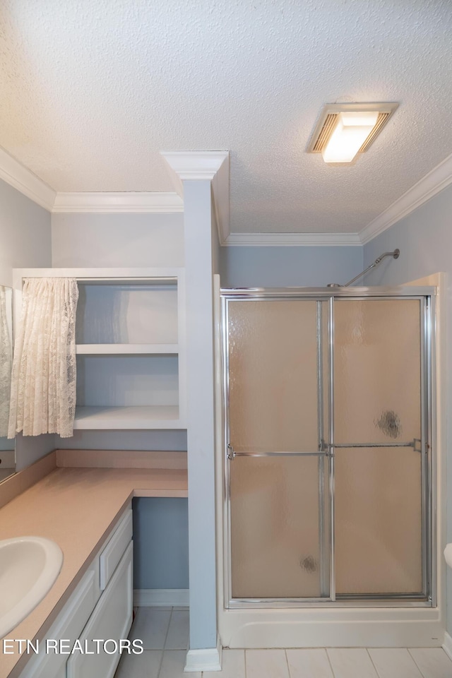 bathroom featuring tile patterned floors, a shower with shower door, a textured ceiling, and ornamental molding