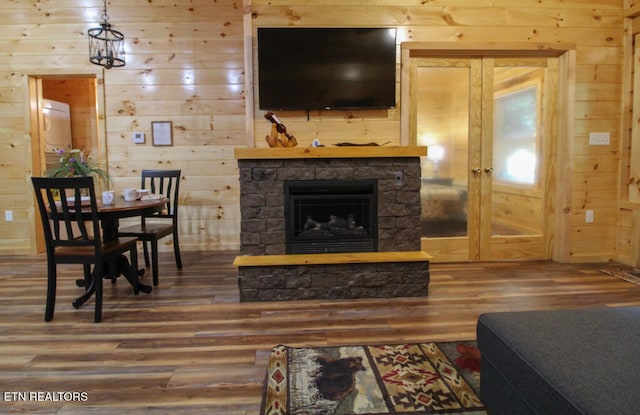 living room with wood walls, a stone fireplace, and wood-type flooring