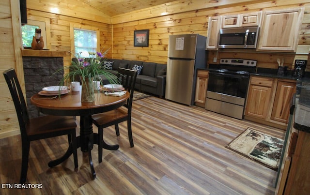 dining room with hardwood / wood-style floors, wood walls, and lofted ceiling