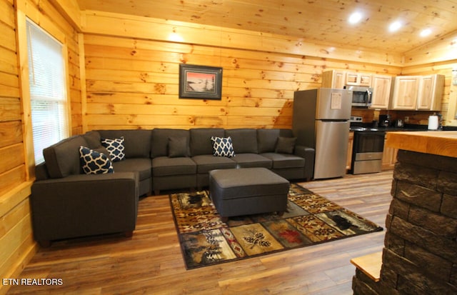 living room featuring wooden walls, lofted ceiling, and light wood-type flooring