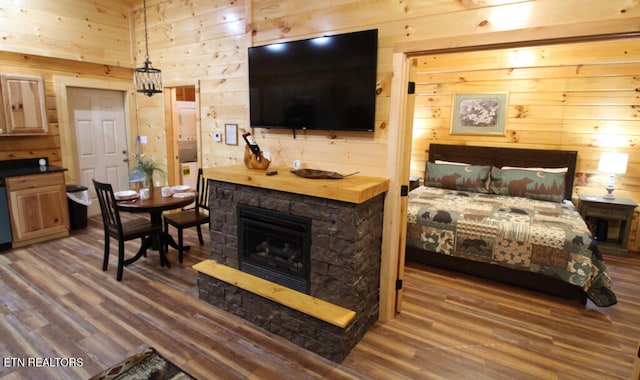 interior space with wood-type flooring, a stone fireplace, and wooden walls