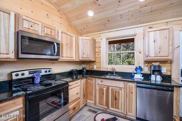 kitchen featuring stainless steel appliances, vaulted ceiling, sink, wooden ceiling, and dark stone countertops